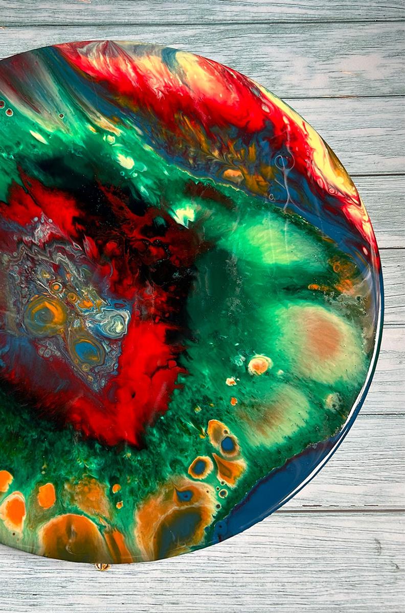 Resin art disk of reds, yellows, blues and greens